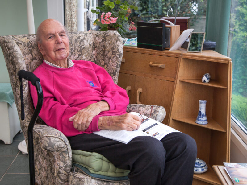 95 years old English man in domestic interior, reading local life magazine. Health, care and medicine concept 95 years old English man in domestic interior, reading local life magazine. Health, care and medicine concept