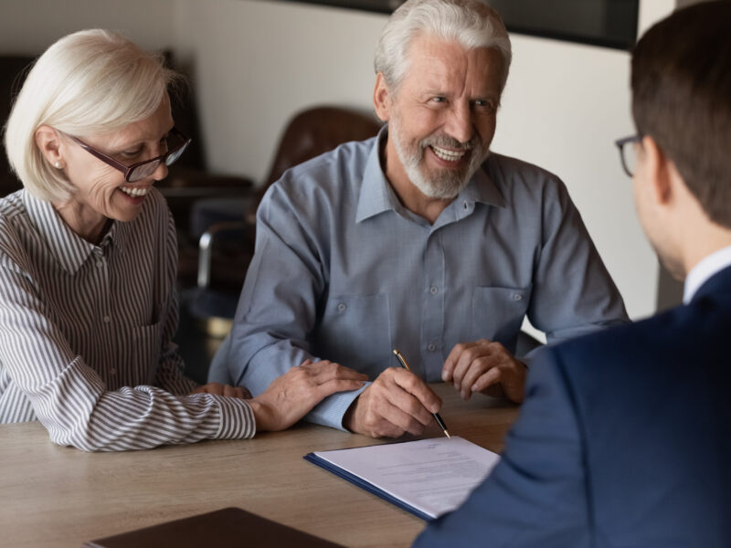 Happy mature family couple of clients consulting legal expert, lawyer, solicitor about legal document signing, asking advice, question, talking, celebrating deal, house or medical insurance buying